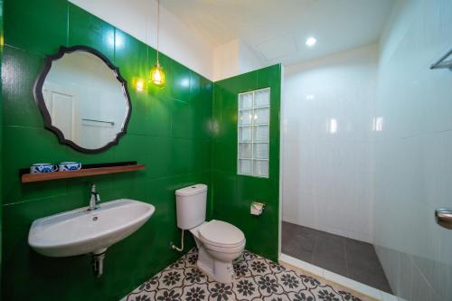 a green bathroom with a toilet and a sink at Nyonya Maison Boutique Hotel Phuket Old Town in Phuket Town