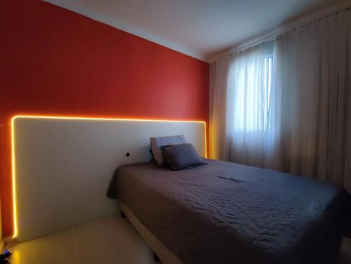 een slaapkamer met een bed met verlichting aan de muur bij Apartamento aconchegante e tranquilo Suzano in Suzano
