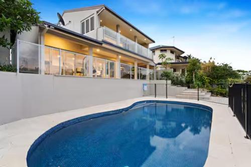 a house with a swimming pool in front of a house at Sorrento Waterfront Retreat & Pool in Gold Coast