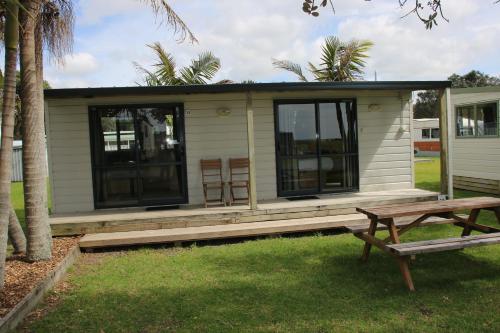 a small house with a bench in front of it at Pakiri Beach Holiday Park in Pakiri