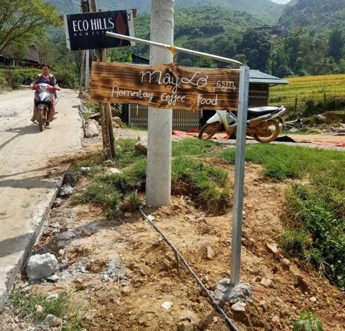 a sign on the side of a road with a person riding a motorcycle at Mẩy Lơ Homestay in Sa Pa
