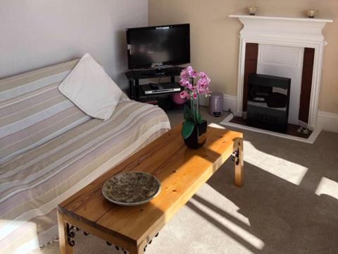 ein Wohnzimmer mit einem Bett und einem Tisch mit Blumen in der Unterkunft St Catherines Court No 7 in Fowey