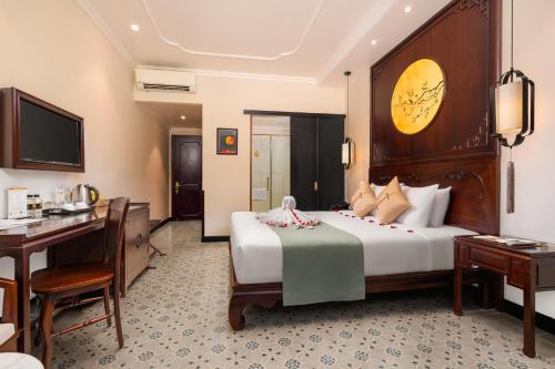 a hotel room with a large bed and a desk at Laluna Hoi An Riverside Hotel & Spa in Hoi An