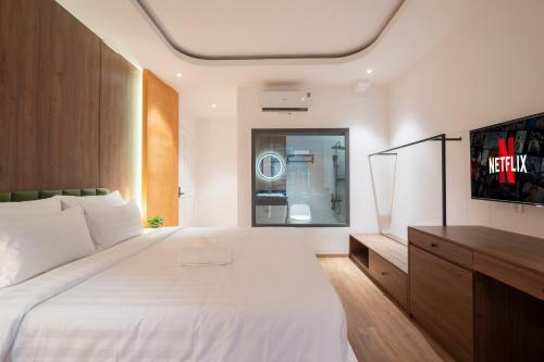 a bedroom with a large white bed and a tv at La Hotel Nguyen Van Dung in Ho Chi Minh City