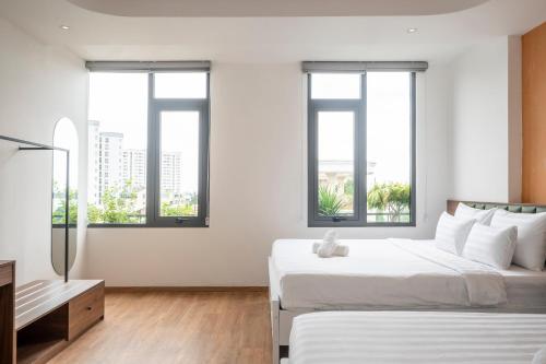 two beds in a white room with windows at La Hotel Nguyen Van Dung in Ho Chi Minh City