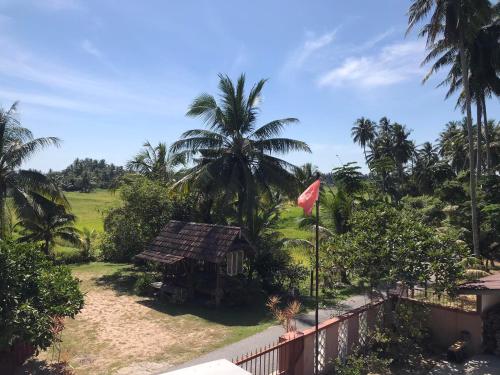 a house with a flag and palm trees at Seri Pengkalan Guest House in Bachok