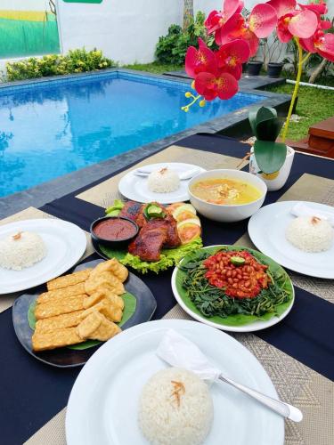 a table topped with plates of food next to a pool at D'svarga Glamping in Seturan