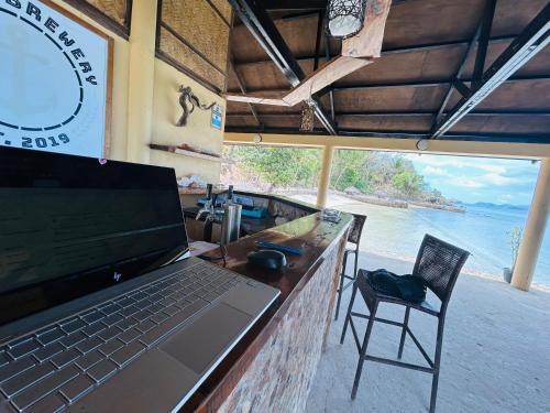 a laptop on a bar with a view of the ocean at Chindonan Dive and Beach Resort in Coron