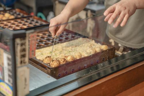 a person is preparing food in a buffet at SEKAI HOTEL Deep Osaka Experience in Osaka