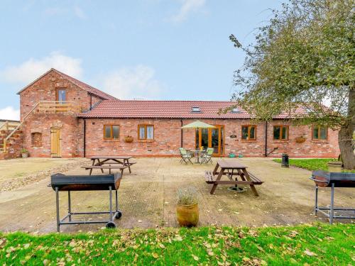un edificio de ladrillo con mesas de picnic delante de él en Bluebell- Uk31533, en Goxhill