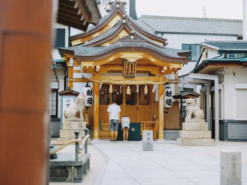 a man standing in front of a shrine at SEKAI HOTEL Deep Osaka Experience in Osaka