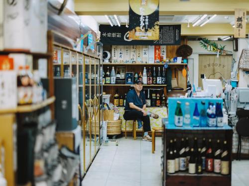 a man sitting in a bar in a shop at SEKAI HOTEL Deep Osaka Experience in Osaka
