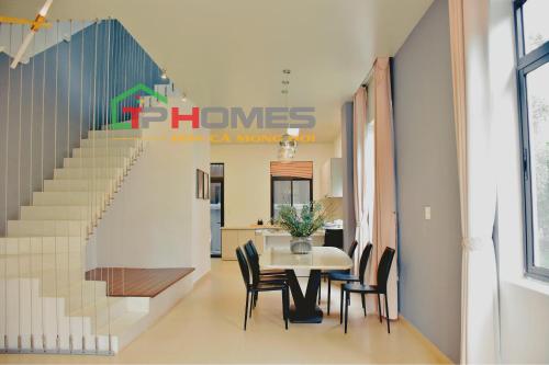 a dining room with a table and chairs and a staircase at TP-HOMES in Ho Chi Minh City