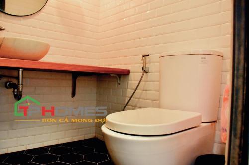 a bathroom with a white toilet and a wooden shelf at TP-HOMES in Ho Chi Minh City