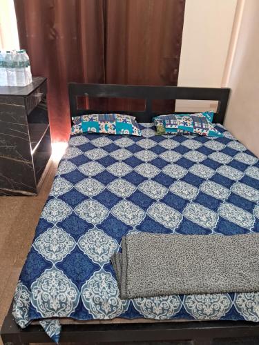 a bed with a blue and white quilt and pillows at Calangute Pristine Guest House in Calangute