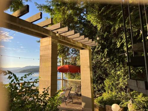 een patio met een parasol en een tafel en stoelen bij SALT COTTAGE Waterfront Guest House with Superb Views in West Vancouver