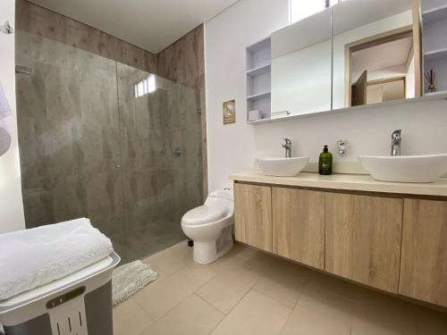 a bathroom with a toilet and two sinks and a shower at Espectacular apto frente al mar in Coveñas