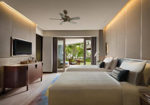 a bedroom with two beds and a flat screen tv at Conrad Bali in Nusa Dua