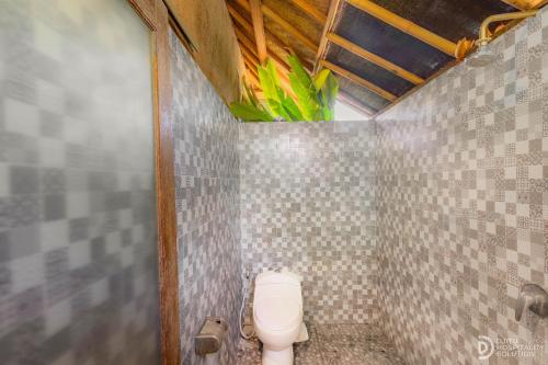 a bathroom with a toilet in a tiled wall at Menjangan View in Banyuwedang