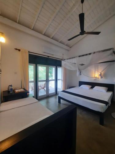 a bedroom with two beds and a ceiling fan at Silver Lake Villa & Boat Safari in Balapitiya