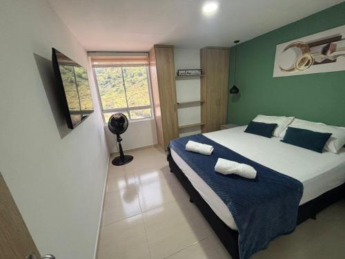 a bedroom with a bed with blue walls and a window at Full Apartamento de descanso vacacional in San Gil