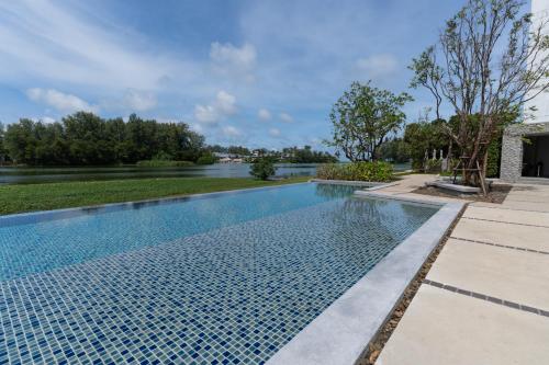 a swimming pool with a lake in the background at Spacious 3BR Sea-View Condo Resort Amenities 2708 in Laguna Phuket