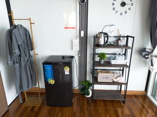 a refrigerator in a room with a shelf and a clock at บ้านนุสรา รีสอร์ท ภูทับเบิก in Ban Maeo Thap Boek