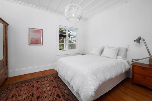 a white bedroom with a bed and a window at Quintessential Russell Cottage in Russell