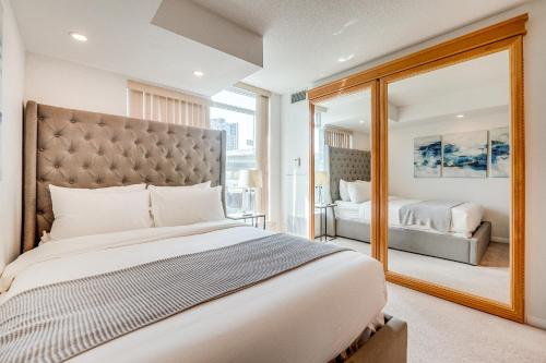 a bedroom with a large bed and a mirror at 2BR Condo - Free Parking - Park & City View in Toronto