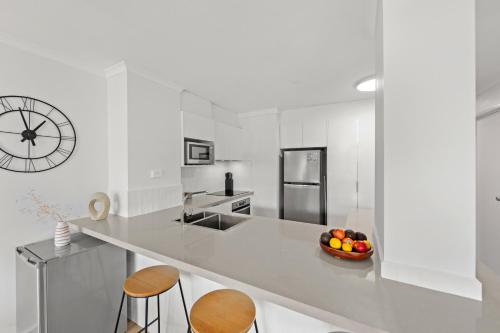 a white kitchen with a bowl of fruit on a counter at Windward Apartments in Mooloolaba