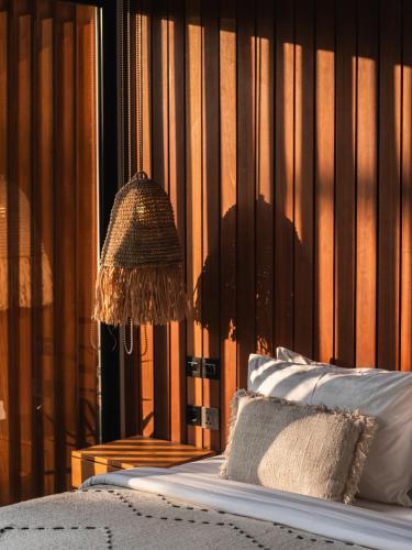 a bedroom with a bed and a lamp on a wall at Blacksand Villas Bingin, Uluwatu by Sandara in Uluwatu