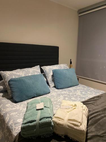 a bed with two pillows and towels on it at Brisa del Sol, next to the airport & MDS Casino in Concepción