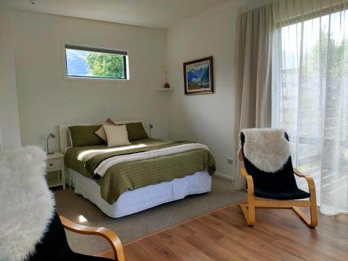 a bedroom with a bed and a chair and a window at Gills Hawea Haven in Lake Hawea