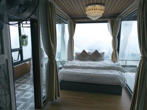a bedroom with a bed and a large window at บ้านนุสรา รีสอร์ท ภูทับเบิก in Ban Maeo Thap Boek