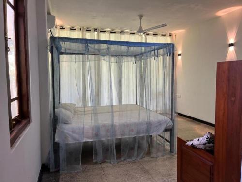 1 dormitorio con cama con dosel y ventana en Sri Holiday House - Hikkaduwa, en Hikkaduwa
