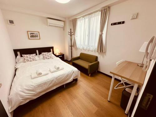 a bedroom with a bed and a chair and a desk at Rest Collection SEIWA LODGE Tokyo in Tokyo
