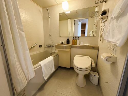a bathroom with a toilet and a sink and a tub at Hokkaido Greenland Hotel Sunplaza in Iwamizawa