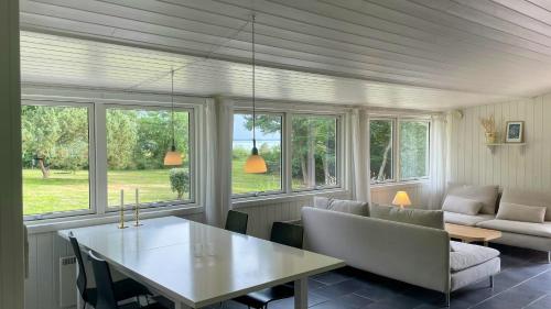 un salon avec une table, des chaises et des fenêtres dans l'établissement Family Cottage At Odden, 100 Meters From The Beach, à Lumsås