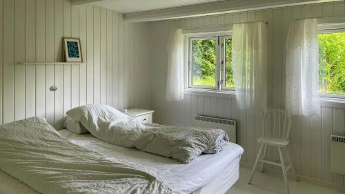 un lit défait dans une chambre avec deux fenêtres dans l'établissement Family Cottage At Odden, 100 Meters From The Beach, à Lumsås
