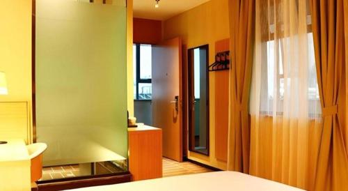 a room with a green wall and a bathroom at IU Hotel Kunming Jinma Bijifang Joy City in Kunming
