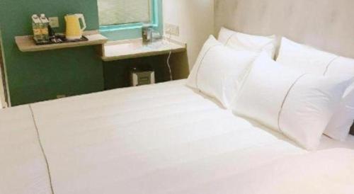 a bed with white sheets and pillows in a room at Magnotel Hotel Suzhou Guanqian Street Pingjiang Road in Suzhou