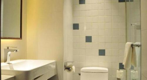 a bathroom with a sink and a toilet and a mirror at Magnotel Hotel Suzhou Guanqian Street Pingjiang Road in Suzhou