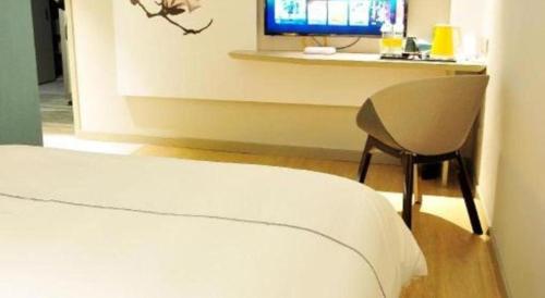 a bedroom with a bed and a desk with a television at Magnotel Hotel Suzhou Guanqian Street Pingjiang Road in Suzhou