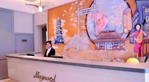 a woman sitting at a reception desk in an office at Magnotel Hotel Suzhou Guanqian Street Pingjiang Road in Suzhou