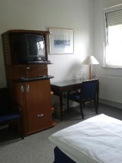 Schlafzimmer mit einem Bett und einem Schreibtisch mit einem TV in der Unterkunft Hotel Alte Wache in Mariental