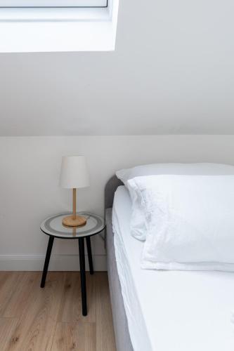 a bed with a night stand next to a table with a lamp at 65m2 Apartment near Vienna - Up to 6 Guests - Self Check-in - Free Parking in Purkersdorf