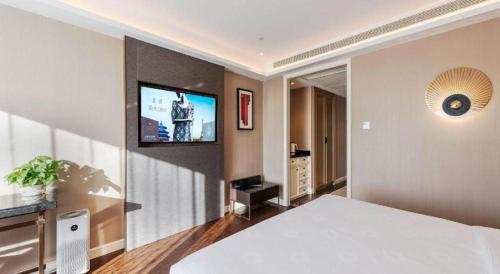 a bedroom with a bed and a flat screen tv at James Joyce Coffetel Harbin West High-speed Railway Station Wanda Plaza in Harbin