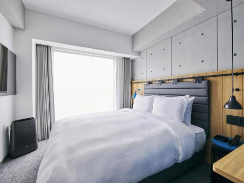 a bedroom with a large white bed and a window at ibis Styles Nagoya in Nagoya