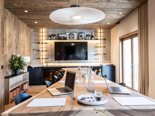 a conference room with a table with two laptops on it at Novotel Megève Mont-Blanc in Megève