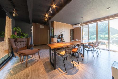 a dining room with a large wooden table and chairs at 瑠璃色の地球 in Katsuura